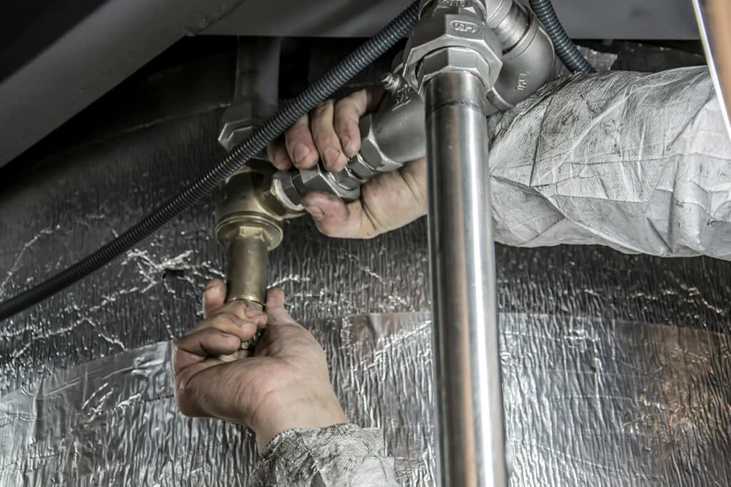 Expert working on pipes, showcasing skills that impact plumber salary and job performance.