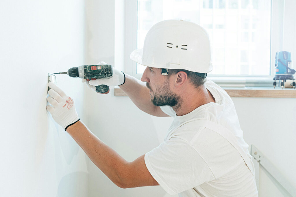 A worker installs a wall outlet, showing hands on skills earned through electrician certification.