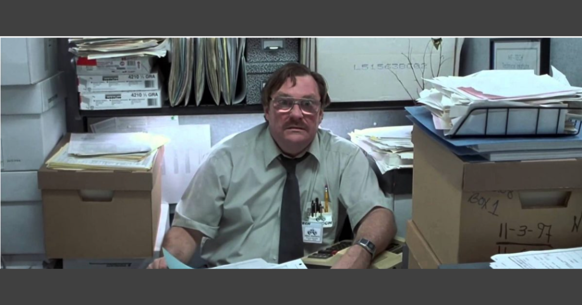 Milton from Office Space sitting at desk