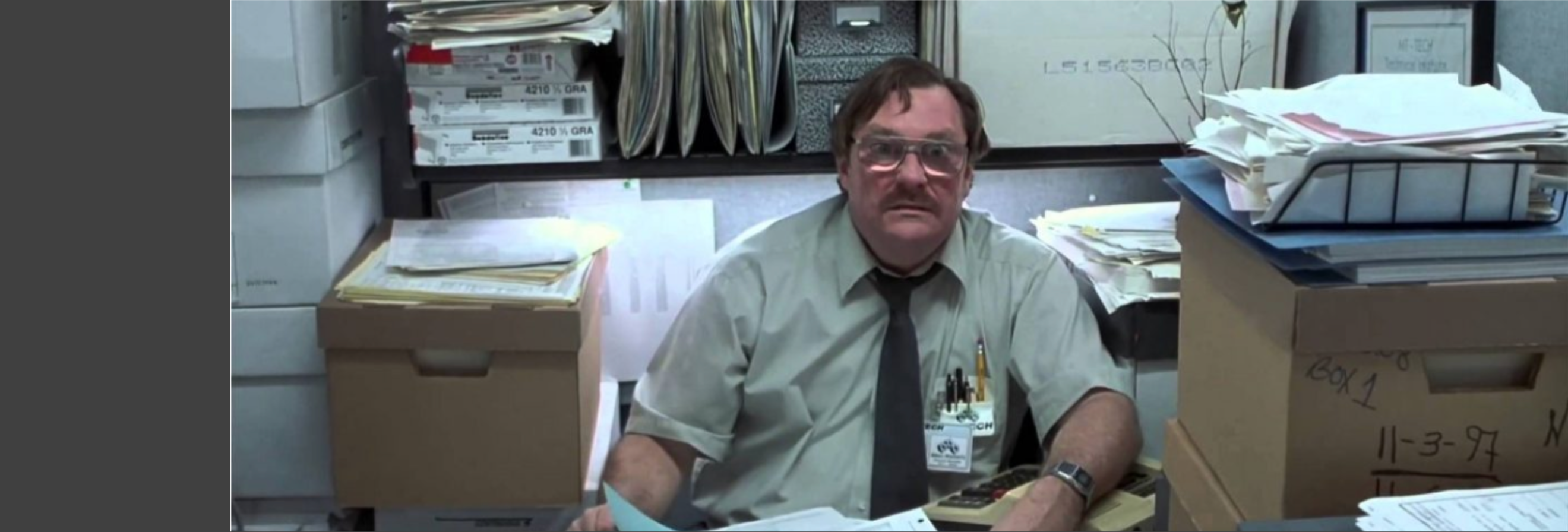 Milton from Office Space sitting at desk